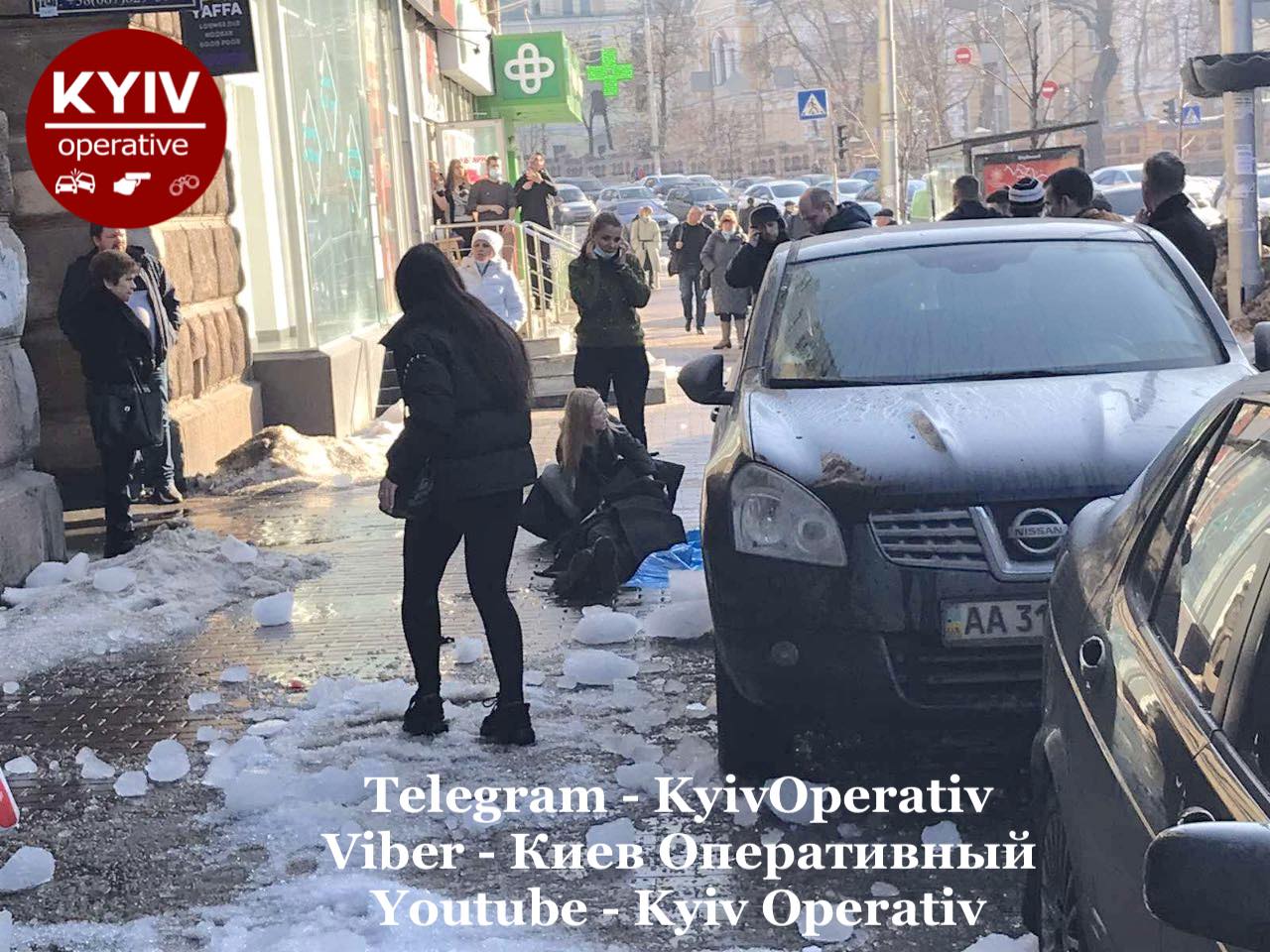 В центрі Києва на дівчину впала величезна брила льоду: її намагаються врятувати пішоходи (фото)