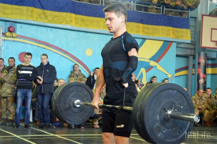 участник соревнования поднимает штангу